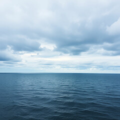A calm blue sea with rolling waves and a distant island silhouetted against a cloudy sky.