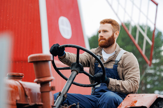 Portrait of handsome bearded man farmer tractor driver on farm