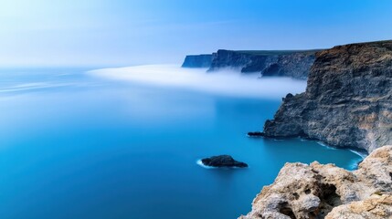 Fototapeta premium High cliffs on the seashore, covered with a light haze of fog, create an atmosphere of mystery and grandeur peculiar to nature. 