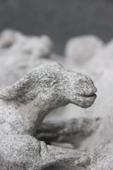 detail of a stone sculpture of a goat in a park, close up