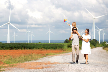 Happiness family walking wind turbine farm while father piggyback of daughter together, environment...
