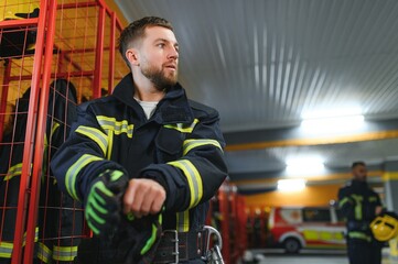 Fireman putting on protective uniform and preparing for action while standing in fire station