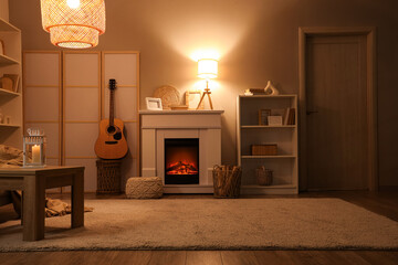 Interior of living room with fireplace, folding screen and glowing lamps in evening