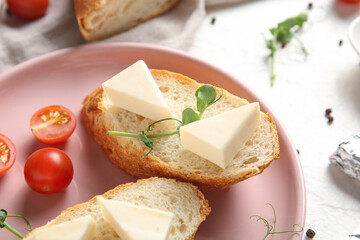 Plate with bread, triangles of tasty processed cheese, tomatoes and micro green on light table, closeup