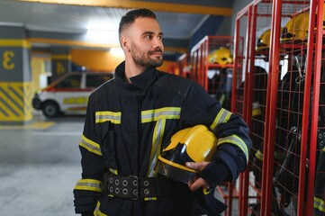 Fireman wearing protective uniform standing in fire department at fire station