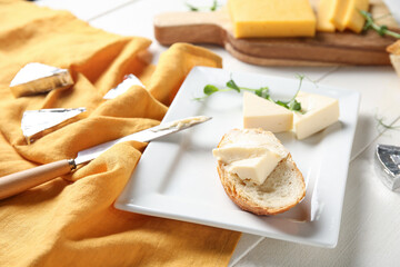 Plate with bread, triangles of tasty processed cheese, micro green and napkin on light wooden table