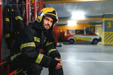 Fireman wearing protective uniform standing in fire department at fire station