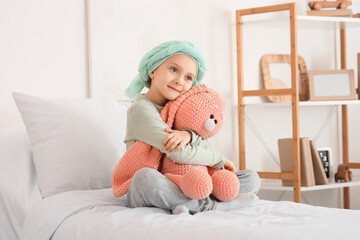 Little girl after chemotherapy with toy bunny on bed in clinic. Childhood cancer awareness concept