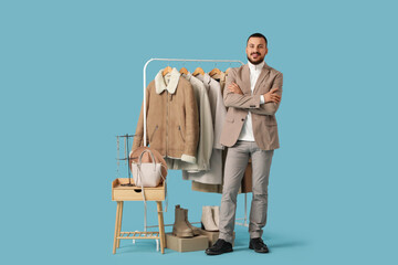Male stylist with warm clothes and accessories on blue background