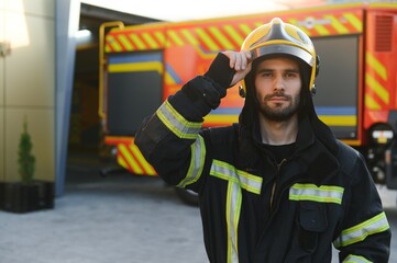Firefighters man in a protective suit near fire truck. Protection, rescue from danger. Fire station