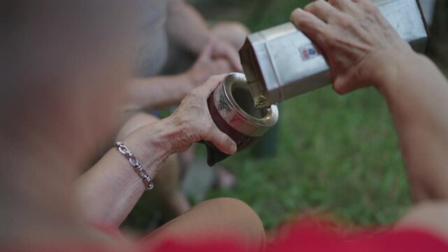 Close-up of a person filling a traditional mate gourd with yerba mate.