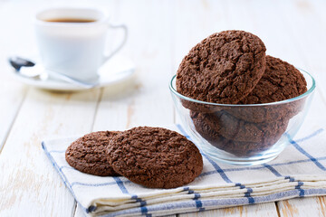 Tasty chocolate brownie cookies with cracks and coffee on a light kitchen table, selective focus.