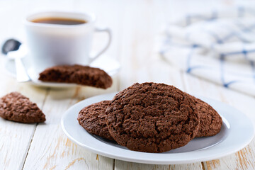 Tasty chocolate brownie cookies with cracks and coffee on a light kitchen table, selective focus.