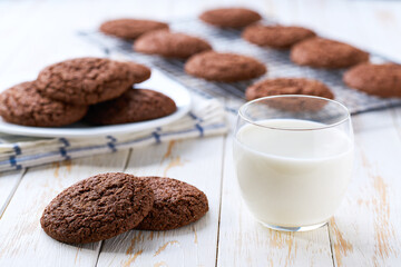 Chocolate cookies and glass milk on a white table, close up.