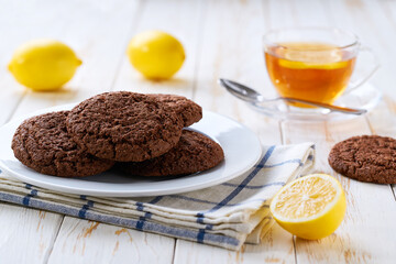 Traditional chocolate cookies and tea on a light kitchen table, selective focus.