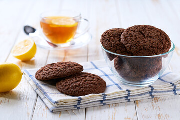 Tasty chocolate brownie cookies with cracks  and tea on a light kitchen table, selective focus.