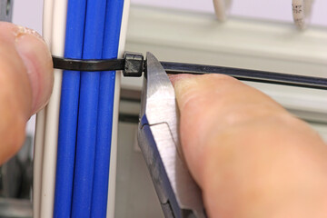Obraz premium Cutting plastic ties on insulated wires with a tool.