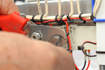 Cutting plastic ties on insulated wires with a tool.