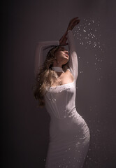 Fototapeta premium Studio shot of a girl in a white dress with artificial snow