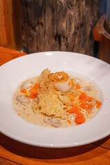 Spaghetti with scallop and truffle sauce decorated with salmon eggs on white dish