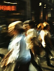 Obraz premium Blurred people in motion are walking down the street. A blurred photo capturing a busy city street scene creating a sense of motion and energy.