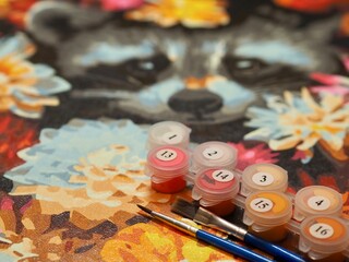 A paint by numbers kit showcases vibrant colors, brushes, and numbered paint pots on a partially...