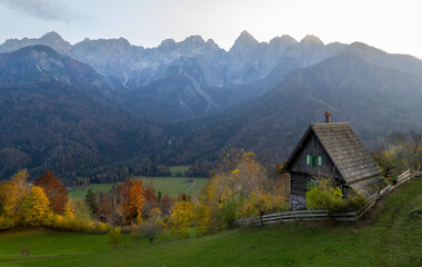 Drone scenery of wooden mountain hut overlooking autumn valley in the julian alps, slovenia