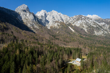 Wooden mountain hut nestled in a lush forest beneath majestic peaks in the julian alps