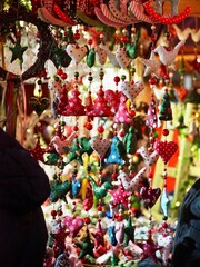 Various colorful hanging decorations, including stars, hearts, and trees, dangle beautifully from a Christmas market stall, creating a vibrant festive atmosphere.