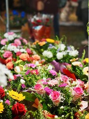 A vibrant market scene with diverse flower arrangements features roses, sunflowers, and more, highlighting the abundance and beauty of natural floral displays.