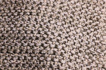 A closeup of a textured beige knitted fabric highlights its intricate detail and craftsmanship