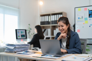 Happy businesswoman working with laptop computer, analyzing data, graphs and charts, making notes and preparing presentation in the office