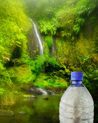 Water fall in a tropical evergreen forest with a plastic bottle in the foreground