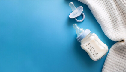 Essentials for baby care featuring a pacifier, baby bottle, and soft blanket on blue background with ample copy space for text placement