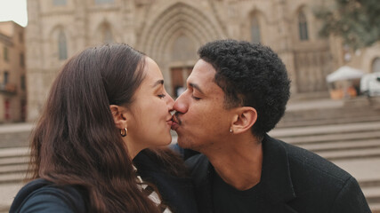 Happy couple standing and kissing in front of historic cathedral, showcasing travel and relationships