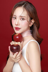 Young Asian Woman Holding Fresh Red Apple on Red Background.