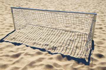 A small soccer goal on sandy terrain, designed for recreational play.