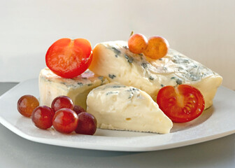 Blue Mold Cheese on White Plate with Tomatoes, Basil, and Grapes in Natural Light