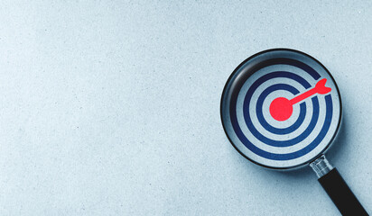 Target board icon in magnifying glass on white paper background. concept of finding goals and setting clear objectives.