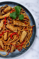 udon noodles, with squid and vegetables, on a marble table, homemade, no people,