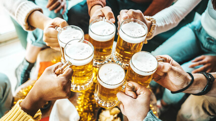 Happy people wearing winter clothes toasting beer glasses at brewery pub table - Festive friends...