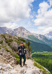 Fototapeta premium Male travel photographer traveling with camera in hand . Hiking through beautiful landscape in Dolomites. Italy. Hobby, professional. Favorite business
