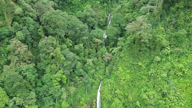 Aerial shot of Curug Cijalu ,beautiful hidden waterfall in green forest. Tropical mountain jungle waterfall in the tropical forest. Nature background