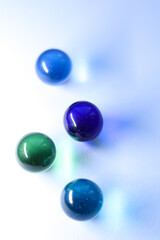 colorful glass marbles dropping colorful reflection on white background