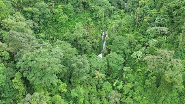 Aerial shot of Curug Cijalu ,beautiful hidden waterfall in green forest. Tropical mountain jungle waterfall in the tropical forest. Nature background
