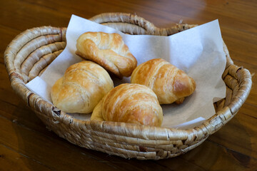 Freshly baked croissants in a woven basket, perfect for a cozy breakfast or brunch setting with a warm, inviting atmosphere.