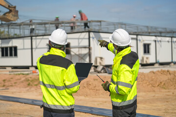 Two surveyor of construction engineer, architect, in hardhat working on construction site.