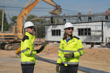 Two surveyor of construction engineer, architect, in hardhat working on construction site.