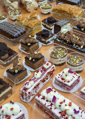 A variety of desserts on a wooden table, including cakes, pastries, and mousses