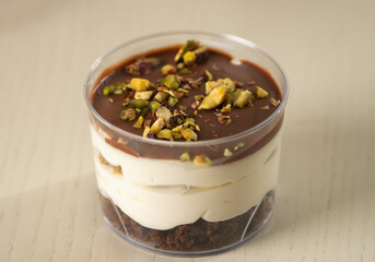 Dessert mousse with chocolate, cream, and crushed pistachios in a plastic serving cup